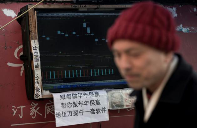 Un boursicoteur explique la volatilité des cours devant son ordinateur à Shanghai, le 25 mars 2018 [Johannes EISELE / AFP]