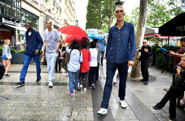 Abdramane Dembele, 2m35, Brahim Takioullah, 2m46, et Arshavir Grigoryan, 2m33, marchent sur les Champs-Elysées à Paris le 1er juin 2018 [GERARD JULIEN / AFP]