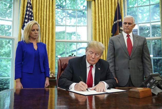 La ministre à la Sécurité intérieure Kirstjen Nielsen et le vice-président Mike Pence regardent le président Donald Trump signant le décret qui met fin à la séparation des familles à la frontière avec le Mexique [Mandel Ngan / AFP]