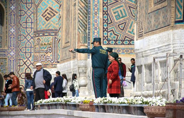 Des membres de la nouvelle "Police des touristes" renseignent des visiteurs de la ville de Samarcande, le 28 mars 2018 en Ouzbékistan [STR / AFP]