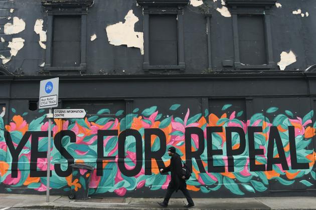 Un homme passe devant un graffiti appelant à voter "Oui", au référendum sur l'avortement en Irlande, à Dun Laoghaire, le 10 mai 2018 [Artur Widak / AFP/Archives]