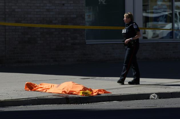 Un corps gît sous un drap à Toronto le 23 avril 2018 après qu'une camionnette a fauché une dizaine de piétons [Lars Hagberg / AFP]