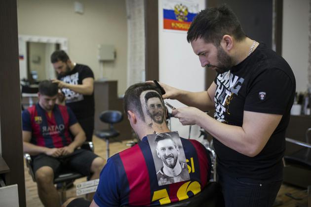 Le coiffeur serbe Mario Hvala dessine Messi sur l'arrière du crâne d'un client à Novi Sad, en Serbie, le 10 juin 2018 [VLADIMIR ZIVOJINOVIC / AFP]