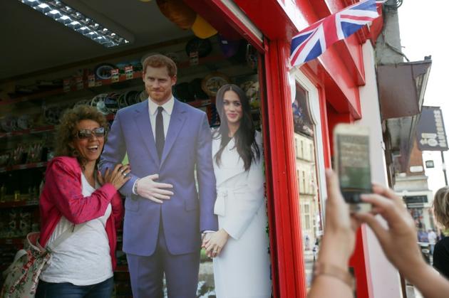 Une touriste pose avec un portrait en carton du prince Harry et de sa fiancée Meghan Markle à Windsor le 8 mai 2018 [Daniel LEAL-OLIVAS / AFP/Archives]