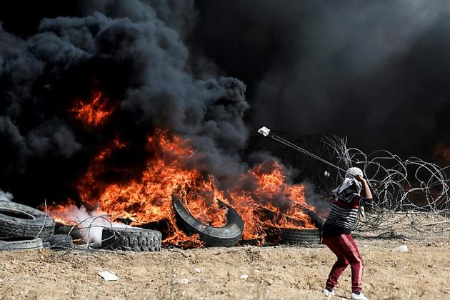 Un manifestant palestinien utilise un lance-pierre lors d'affrontements avec les forces israéliennes à l'est de Gaza, à la frontière avec Israël le 27 avril 2018 [MAHMUD HAMS / AFP]