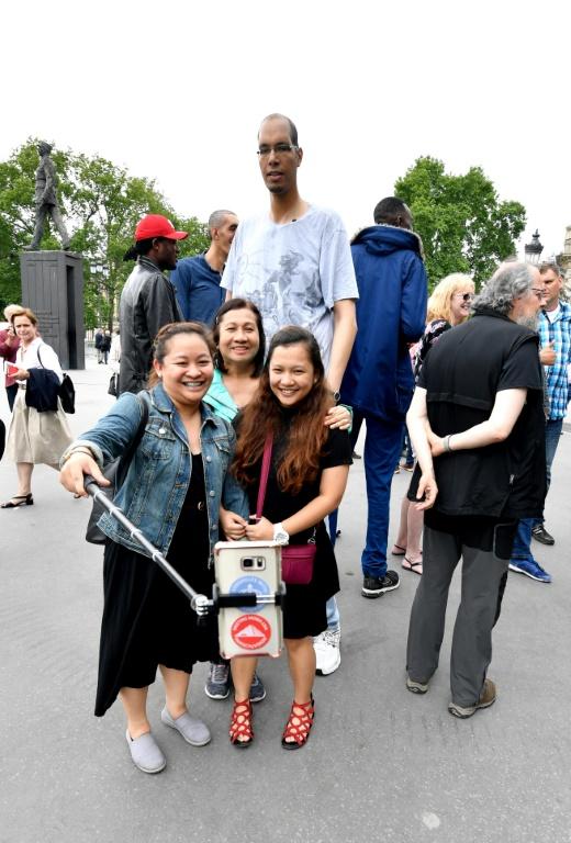 Des touristes font des selfies avec Brahim Takioullah, 2m46, sur les Champs-Elysées à paris le 1er juin 2018  [GERARD JULIEN / AFP]