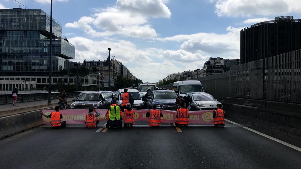 À Paris, des militants écologistes bloquent un pont en se collant les mains au bitume