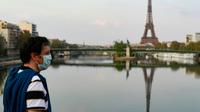 Un passant portant un masque traverse un pont sur la seine à Paris, le 11 avril 2020 [Ludovic MARIN / AFP]
