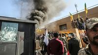 Des membres et partisans du Hachd al-Chaabi, coalition de paramilitaires dominée par des factions pro-Iran, incendient une tourelle devant l'ambassade des Etats-Unis à Bagdad le 31 décembre 2019 [Ahmad AL-RUBAYE / AFP]