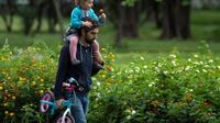 Un homme porte sa petite fille sur les épaules dans un parc à Séville, en Espagne, le 26 avril 2020 [CRISTINA QUICLER / AFP]