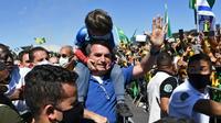Le président brésilien Jair Bolsonaro porte le fils d'un de ses partisans lors d'un rassemblement à Brasilia le 31 mai 2020 [EVARISTO SA / AFP]