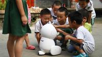 Des enfants de l'école maternelle Yiswind en Chine autour du robot Keeko, le 30 juillet 2018 [GREG BAKER / AFP]