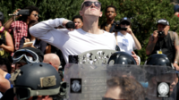 Un homme mime un égorgement alors qu'il marche dans un cortège de l'alt-right