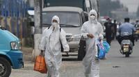 Deux Chinoises en combinaison intégrale de protection passent près du marché de Xinfadi, fermé après l'apparition de nouveaux cas de coronavirus, le 13 juin 2020 à Pékin [GREG BAKER / AFP]