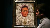 Un employé du musée Victoria & Albert Museum de Londres devant un autoportrait de Frida Kahlo lors d'une exposition consacrée à l'artiste mexicaine, le 13 juin 2018 [Daniel LEAL-OLIVAS / AFP]