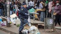 Un policier tient un fusil pour disperser la foule devant un supermarché, le 28 mars 2020 à Johannesburg, en Afrique du Sud [MARCO LONGARI / AFP]