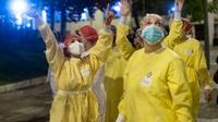 Des personnels soignants saluent les personnes qui les applaudissent devant l'Hôpital de Barcelone, le 13 avril 2020 en Espagne [Josep LAGO / AFP]