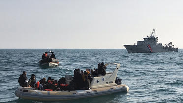 Des secouristes britanniques aident des migrants sur un bateau semi-rigide