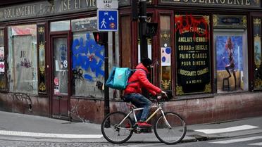 A Paris, un livreur passe devant une boulangerie à l'abandon. 