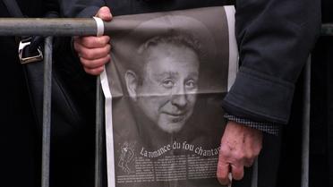 Un homme tient une photographie de Charles Trenet, le 23 février 2001 devant l'église de la Madeleine à Paris [Joel Saget / AFP/Archives]