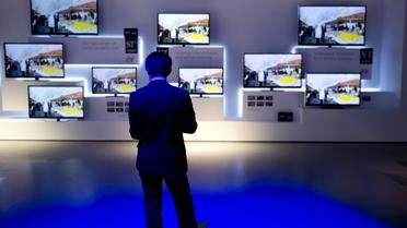 Un homme se tient devant des écrans plasma Panasonic lors d'un salon en Allemagne en 2012 [Odd Andersen / AFP/Archives]