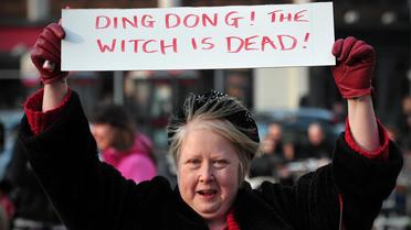 Une femme avec une pancarte indiquant "Ding Dong ! La sorcière est morte", durant un rassemblement après le décès de Margaret Thatcher, le 8 avril 2013 à Londres [Carl Court / AFP]