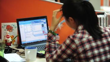 Une femme travaille sur son ordinateur à Pékin [Frederic J. Brown / AFP/Archives]