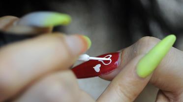 Une femme s'applique du vernis à ongle [Sam Yeh / AFP/Archives]