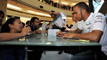 Le pilote de Formule 1 Lewis Hamilton signe des autographes à Kuala Lumpur, en Malaisie, le 20 mars 2013 [Najjua Zulkefli / AFP]