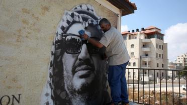 Un homme nettoie le portrait de l'ancien leader palestinien le 29 août 2012 à Ramallah [Abbas Momani / AFP/Archives]