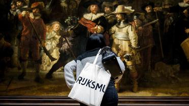 Un visiteur examine la célèbre toile de Rembrandt "la Ronde de nuit" le 4 avril 2013 au musée Rijksmuseum à Amsterdam qui vient de réouvrir ses portes [Koen van Weel / ANP/AFP]
