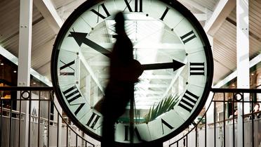 Une personne passe devant une horloge [Jeff Pachoud / AFP/Archives]