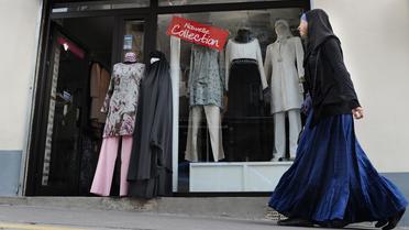 Une femme voilée passe devant une boutique vendant des tenues islamiques, à Paris, en avril 2011 [Miguel Medina / AFP/Archives]