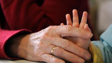 La main d'un enfant dans celle d'une personne âgée [Franck Fife / AFP/Archives]