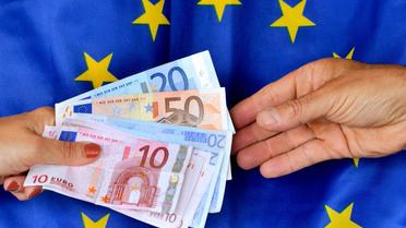 Echange de billets en euros sur fond de drapeau européen [Philippe Huguen / AFP/Archives]