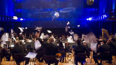 Des musiciens de l'orchestre Brussels Philharmonic jettent des partitions en l'air, le 7 novembre 2012 à Bruxelles [Aurore Belot / Belga/AFP]
