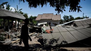 Un homme marche près d'un bâtiment effondré dans le village de Sugian sur l'île indonésienne de Lombok secouée par une série de séismes, le 20 août 2018 [str / AFP]