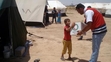 Un volontaire du Croissant Rouge irakien donne un kit humanitaire à un garçon déplacé à Khanaqin près de la frontière avec l'Iran, le 13 juillet 2014 [Younis al-Bayati / AFP/Archives]
