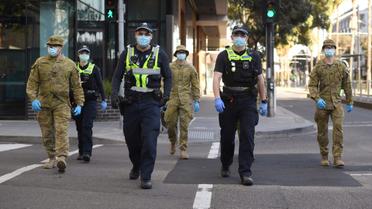 Des policiers et des soldats en patrouille à Melbourne (Australie) le 2 août 2020 après l'instauration d'un couvre-feu en raison du coronavirus [William WEST / AFP]