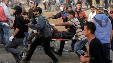 Un manifestant palestinien évacué après avoir été blessé lors de heurts avec les forces de sécurité israéliennes à la frontière entre la bande de Gaza et Israël, le 13 avril 2018  [MAHMUD HAMS / AFP]