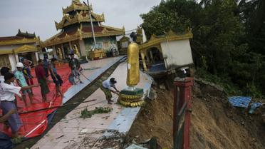 Des ouvriers déplacent une statue de Bouddha de la pagode Kyeik Than Lan, dans le sud de la Birmanie, endommagée par un glissement de terrain, le 18 juin 2018 [Ye Aung THU / AFP]