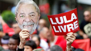 Un partisan de Lula brandit un masque représentant le visage de l'ancien président brésilien et une pancarte "Lula libre" au lendemain de sa libération, lors d'un rassemblement devant le siège des métallos de Sao Bernardo do Campo, près de Sao Paulo, le 9 novembre 2019 [Miguel SCHINCARIOL / AFP]