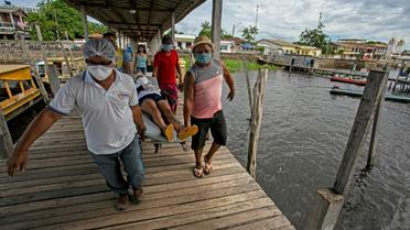 Un patient présentant des symptômes du coronavirus est porté sur un brancard avant son transfert pour un hôpital par voie fluviale, à Melgaço (Brésil), le 10 juin 2020 [TARSO SARRAF / AFP]