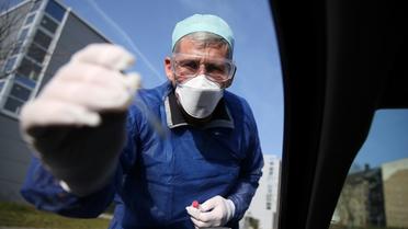 Un médecin allemand teste un automobiliste pour vérifier s'il est positif ou non au coronavirus le 27 mars 2020 à Halle, dans l'est de l'Allemagne. [Ronny Hartmann / AFP]