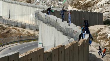 Des Palestiniens debout sur le mur séparant la ville d'Abu Dis en Cisjordanie et Jérusalem est le 28 octobre 2015 [Ahmad Gharabli / AFP/Archives]