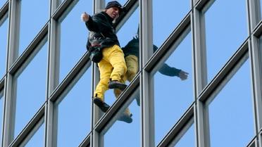 Le "Spiderman français", Alain Robert, escalade à mains nues la tour Total du quartier d'affaires de la Défense, le 21 mars 2016 [JACQUES DEMARTHON / AFP]