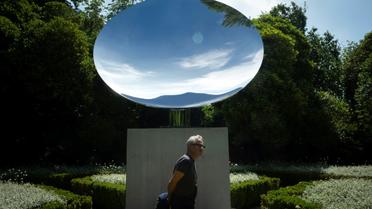 Le sculpteur britannique Anish Kapoor devant son oeuvre "Sky Mirror" lors de la présentation de l'exposition "Anish Kapoor: œuvres, pensées, expériences", le 6 juillet 2018 dans le parc de la Fondation Serralves, à Port, au Portugal [MIGUEL RIOPA / AFP]