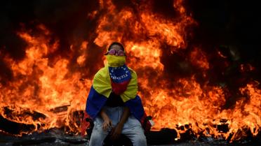 Un manifestant assis devant une barricade en flammes lors d'une manifestation à Caracas, le 24 avril 2017 [Ronaldo SCHEMIDT / AFP/Archives]