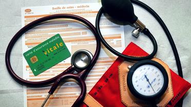 Une feuille de soins, une Carte d'assurance maladie Vitale, d'un stétoscope et d'un tensiomètre, dans un cabinet médical [Philippe Huguen / AFP/Archives]