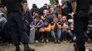 Des policiers croates devant des migrants et réfugiés qui attendent d'entrer dans le centre de transit d'Opatovac en Croatie, le 22 septembre 2015 [Federico Scoppa / AFP]